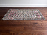 an antique caucasian rug with an ivory field and a pink and brown trellis pattern