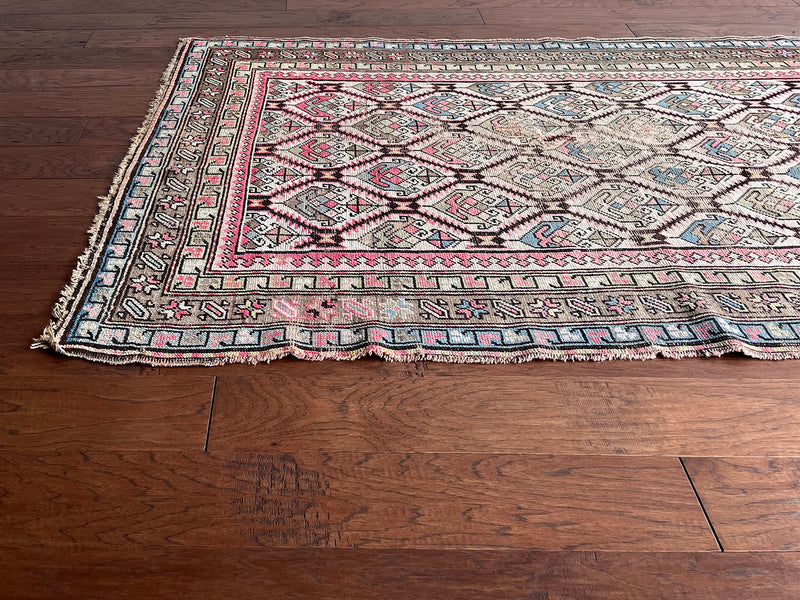 an antique caucasian rug with an ivory field and a pink and brown trellis pattern