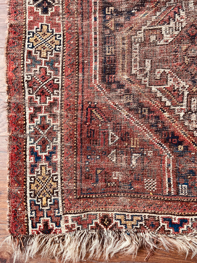 a small vintage shiraz rug with a warm brown, red and coral palette