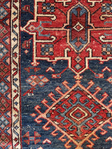a mini antique heriz rug with a dark blue abrash field and red medallions