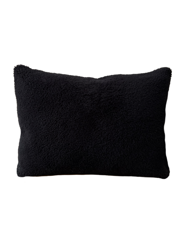 a black shearling lumbar with a plush velvet backing and exposed brass zipper