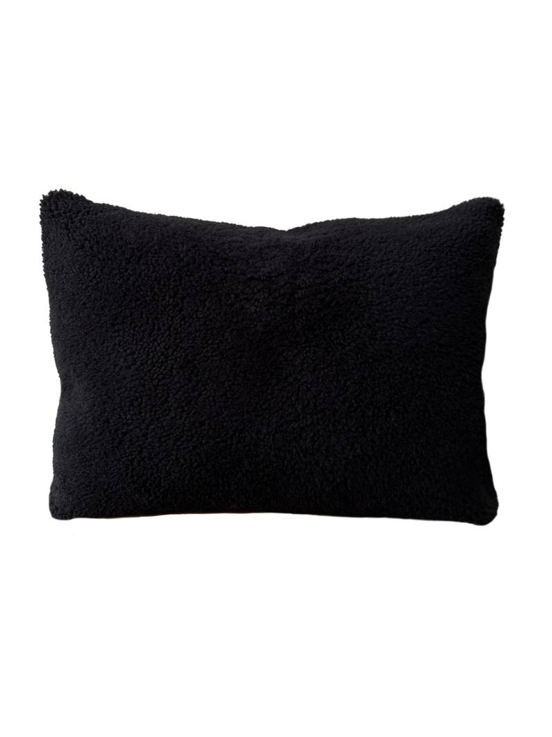 a black shearling lumbar with a plush velvet backing and exposed brass zipper