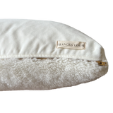 a white shearling pillow backed in plush velvet, with an exposed brass zipper