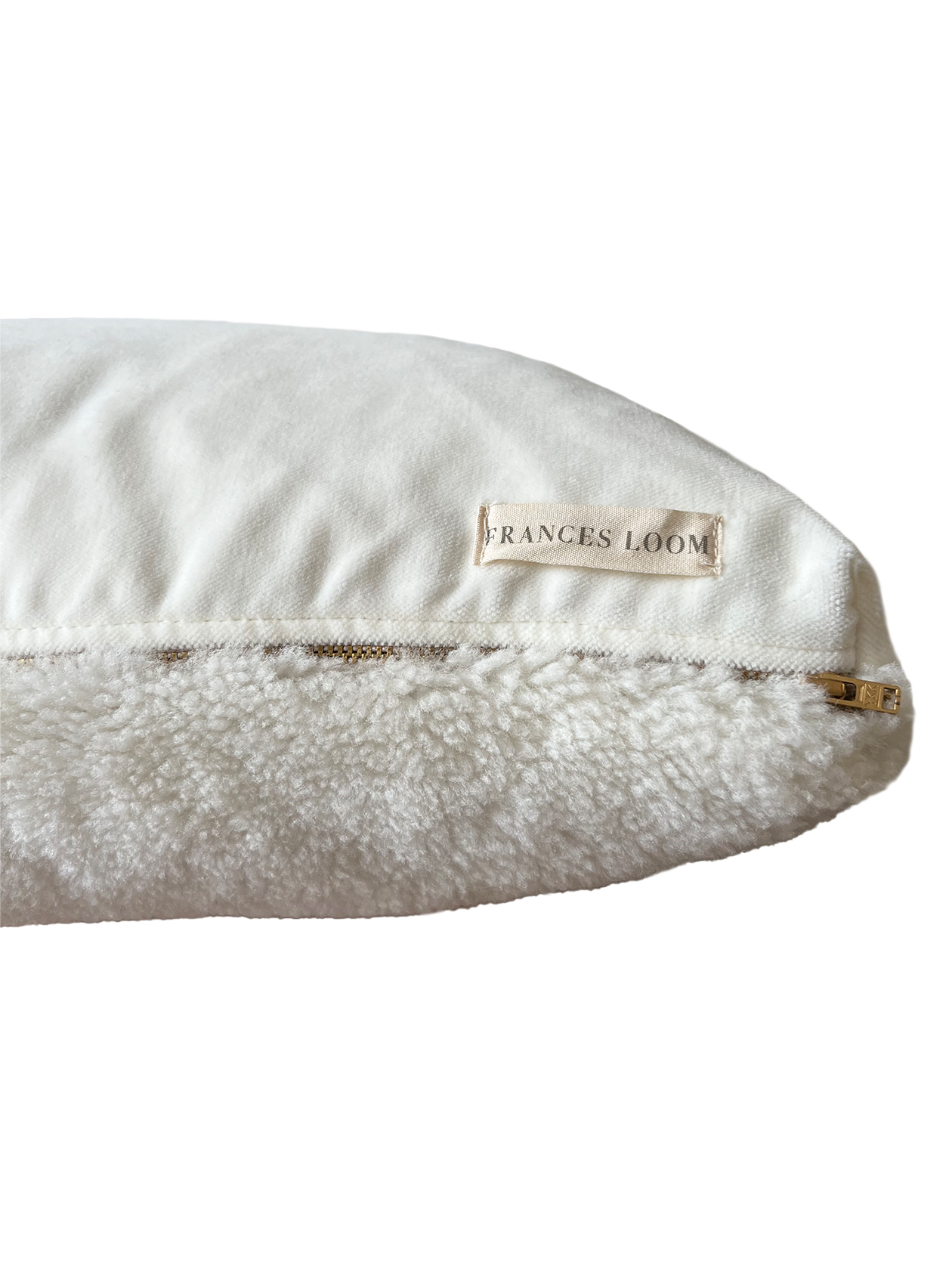 a white shearling pillow backed in plush velvet, with an exposed brass zipper