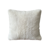 a white shearling pillow backed in plush velvet, with an exposed brass zipper