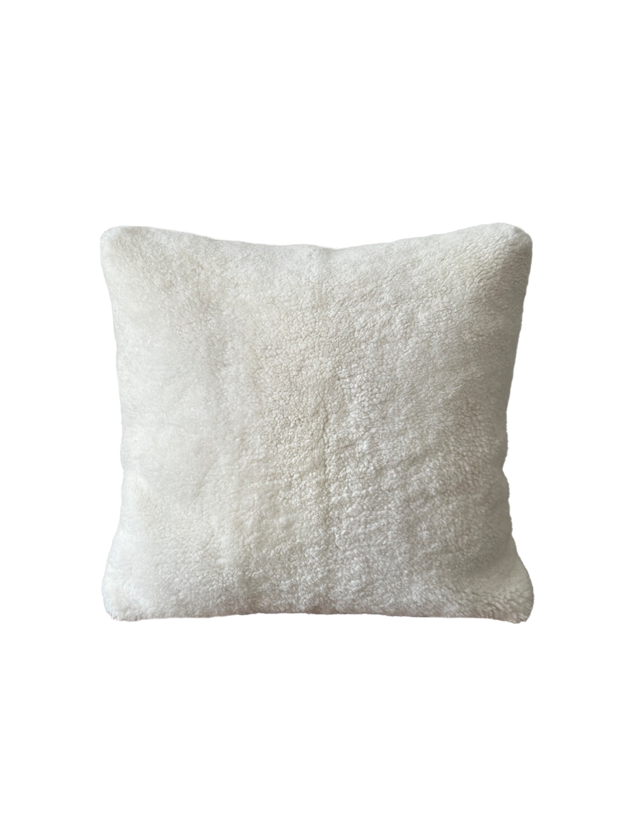 a white shearling pillow backed in plush velvet, with an exposed brass zipper