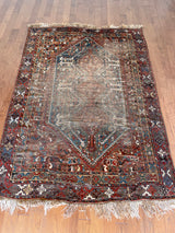 an antique shiraz rug with earthy tones in teal blue and mud red tones