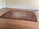 an antique shiraz rug with earthy tones in teal blue and mud red tones