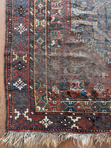 an antique shiraz rug with earthy tones in teal blue and mud red tones