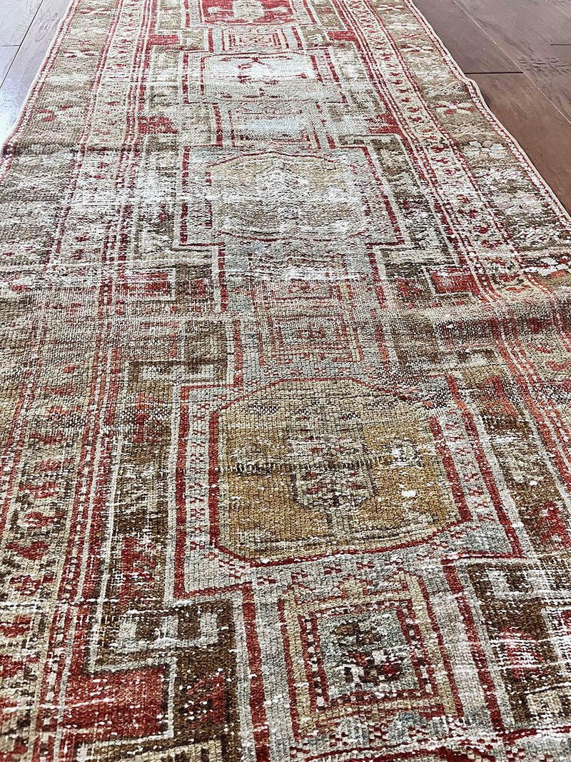 a beautiful antique heriz karajah runner with a brown and brick red palette and lemon yellow accents