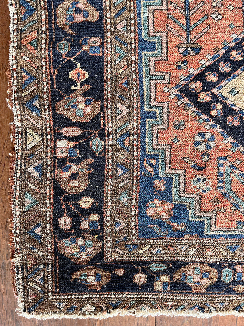 an antique heriz rug with a coral field, dark blue medallions and dark lighter blue accents