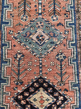 an antique heriz rug with a coral field, dark blue medallions and dark lighter blue accents