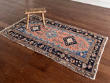 an antique heriz rug with a coral field, dark blue medallions and dark lighter blue accents