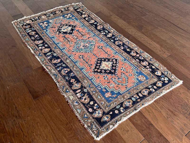 an antique heriz rug with a coral field, dark blue medallions and dark lighter blue accents