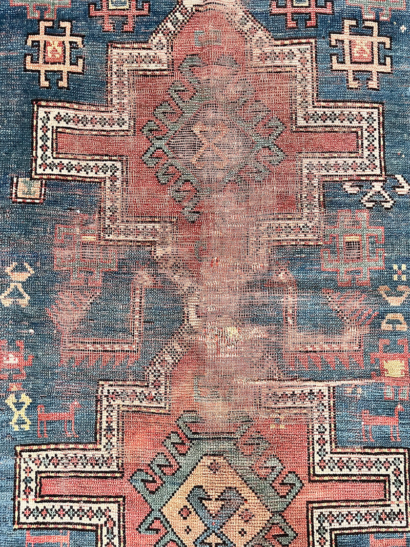 an antique caucasian kazak rug with a teal/blue field and large geometric medallions in a coral/terracotta tone 