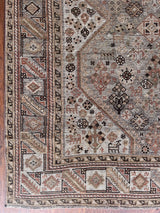 an antique qashqai rug with a greeny grey field and coral accents