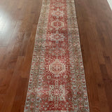an antique heriz karajah runner with a dark coral field and icy blue and teal accents