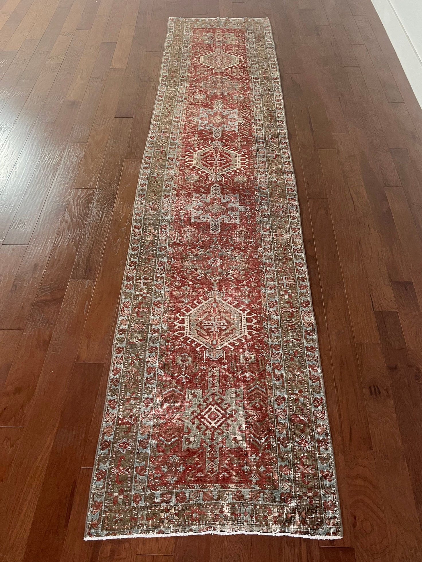 an antique heriz karajah runner with a dark coral field and icy blue and teal accents