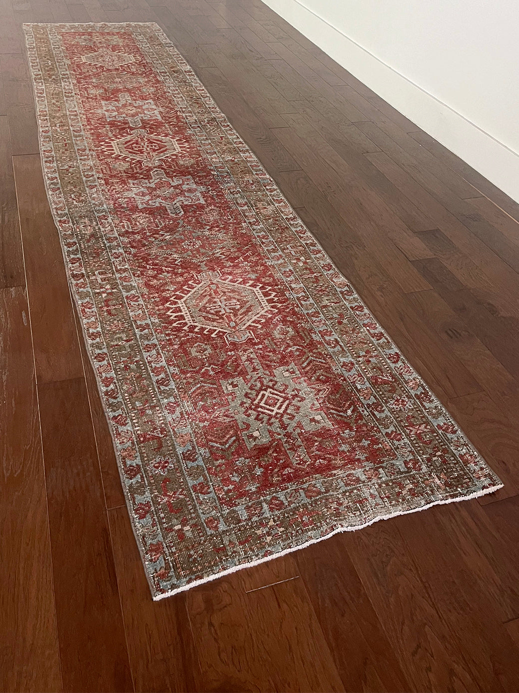 an antique heriz karajah runner with a dark coral field and icy blue and teal accents