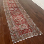 an antique heriz karajah runner with a dark coral field and icy blue and teal accents