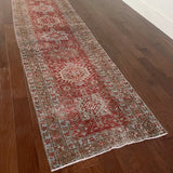 an antique heriz karajah runner with a dark coral field and icy blue and teal accents