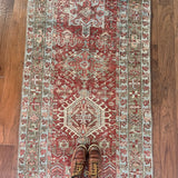 an antique heriz karajah runner with a dark coral field and icy blue and teal accents
