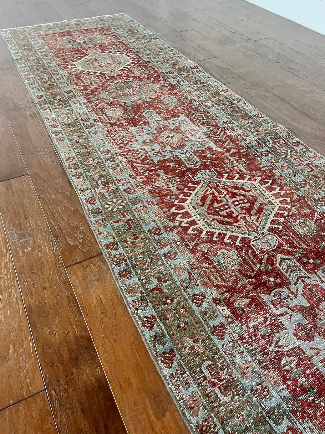 an antique heriz karajah runner with a dark coral field and icy blue and teal accents