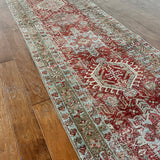 an antique heriz karajah runner with a dark coral field and icy blue and teal accents