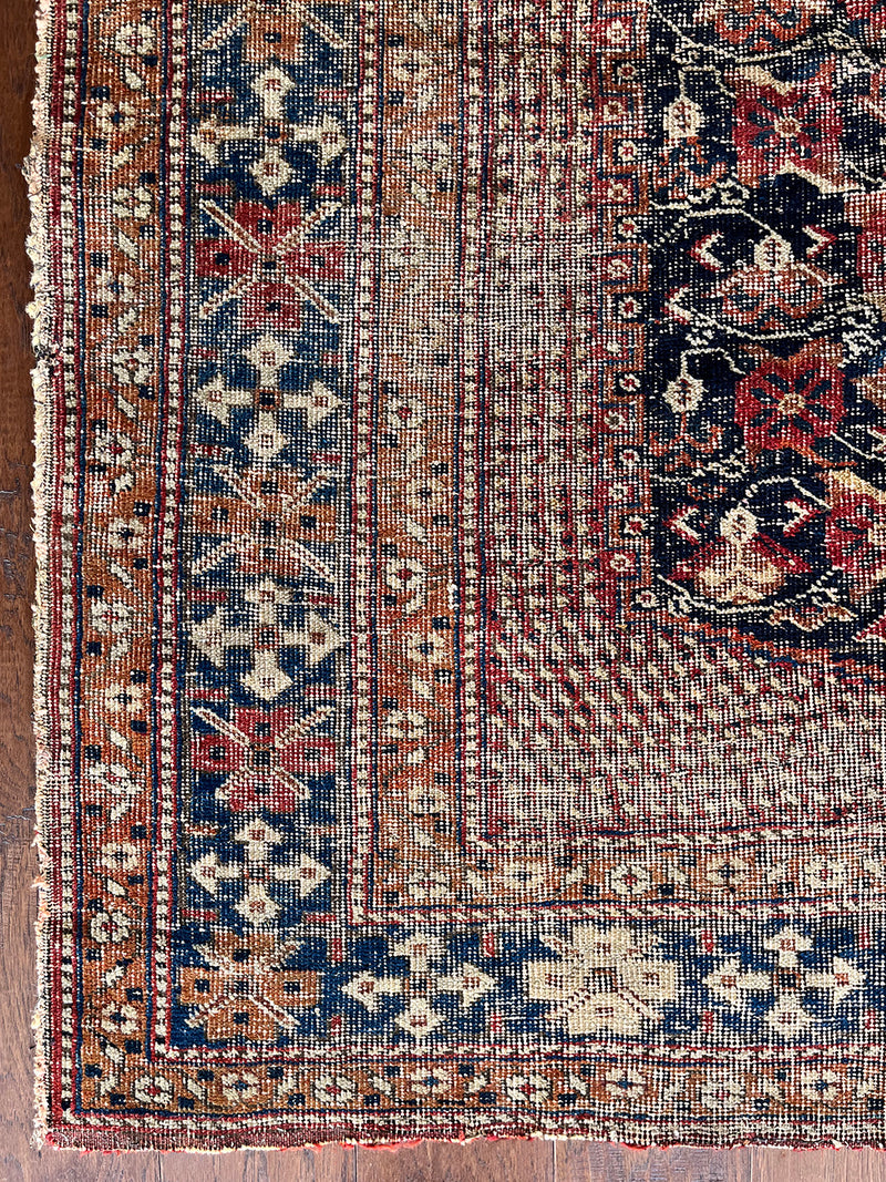 an antique afshar rug with a midnight blue medallion, intricate floral pattern and dot details 