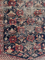 an antique afshar rug with a midnight blue medallion, intricate floral pattern and dot details 