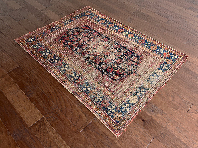 an antique afshar rug with a midnight blue medallion, intricate floral pattern and dot details 