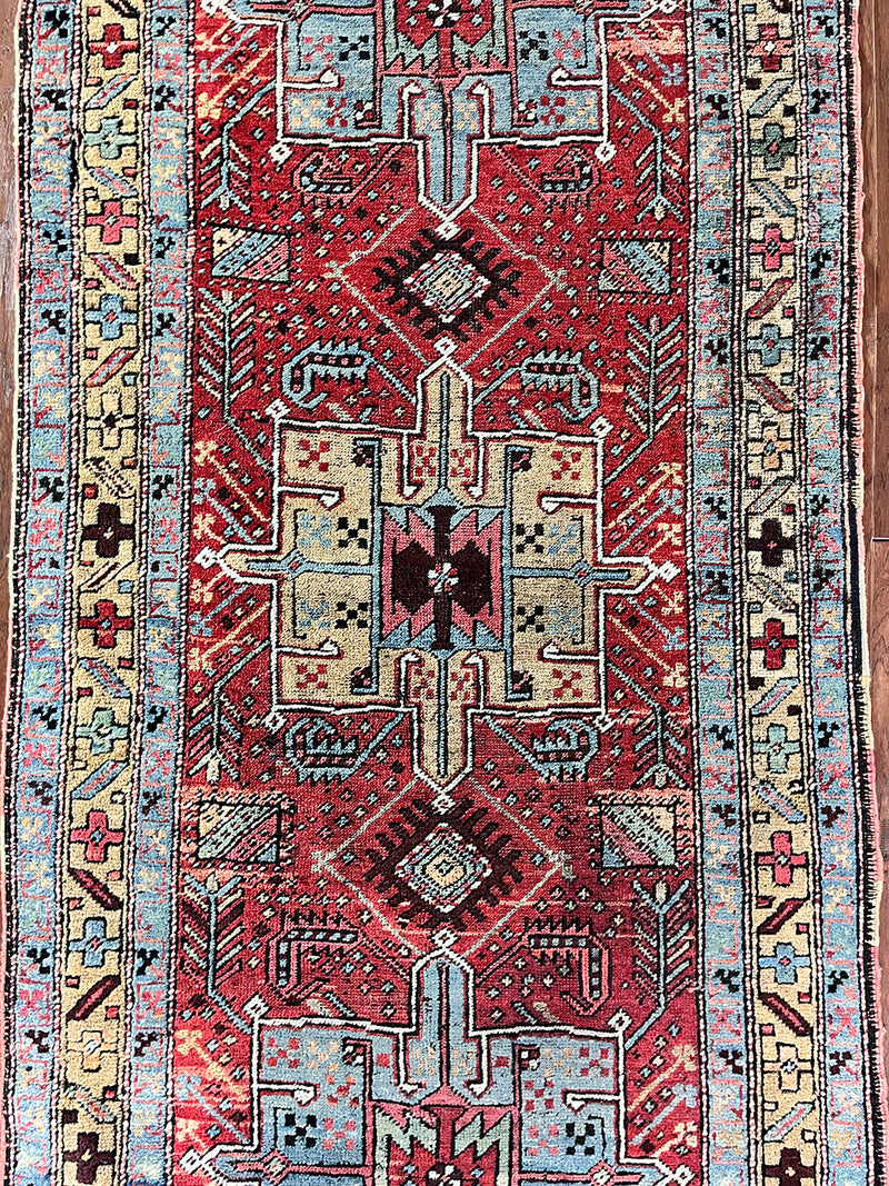 an antique heriz runner with a dark red field and bright turquoise and green medallions