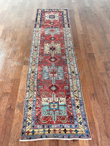 an antique heriz runner with a dark red field and bright turquoise and green medallions