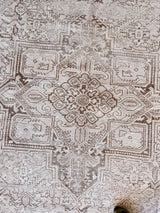 a large heriz rug with a neutral palette and a large central medallion in light taupe tones