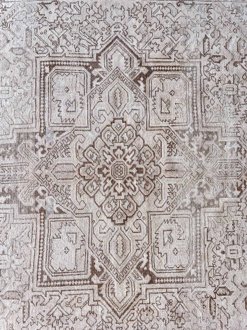 a large heriz rug with a neutral palette and a large central medallion in light taupe tones