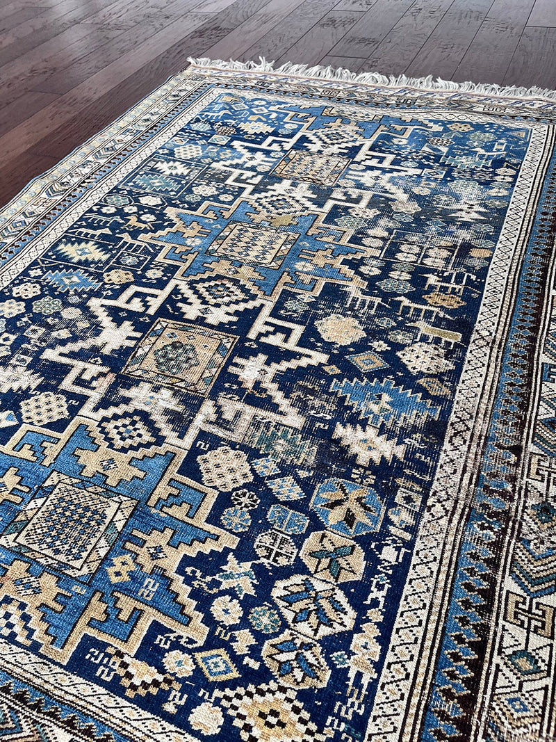 an antique caucasian rug with a blue palette and geometric pattern