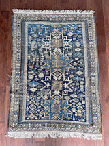 an antique caucasian rug with a blue palette and geometric pattern