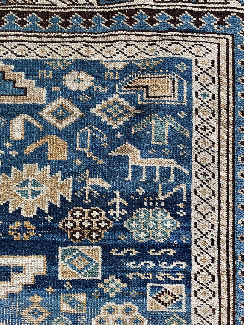 an antique caucasian rug with a blue palette and geometric pattern