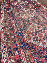 an antique shiraz rug with cream medallions and a delicate stripe pattern