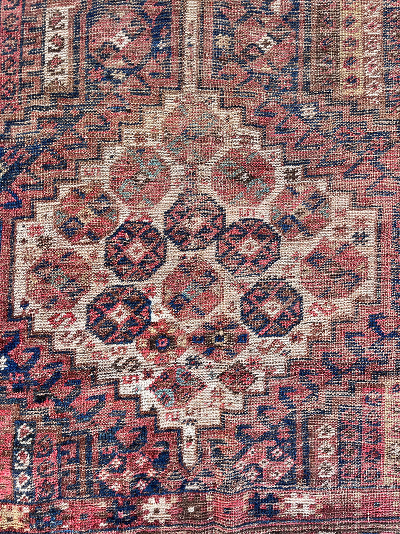 an antique shiraz rug with cream medallions and a delicate stripe pattern