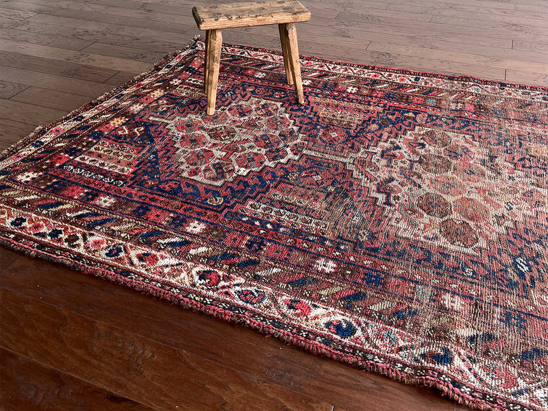 an antique shiraz rug with cream medallions and a delicate stripe pattern