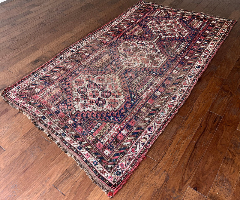 an antique shiraz rug with cream medallions and a delicate stripe pattern