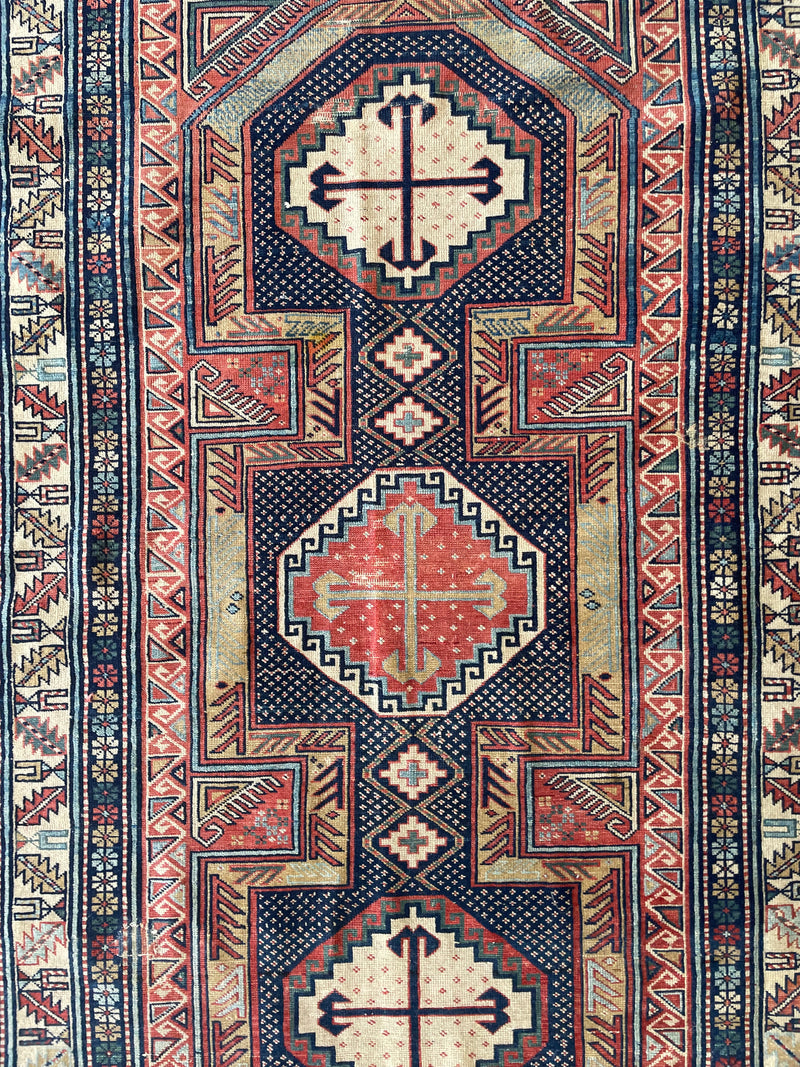 a colorful caucasian rug with red, yellow, green and blue hues and a pretty floral border