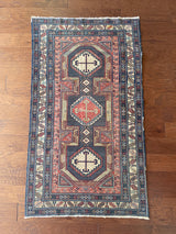 a colorful caucasian rug with red, yellow, green and blue hues and a pretty floral border