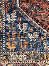 a large vintage qashqai rug with a burnt orange field and blue medallions