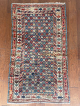 an antique caucasian rug with a light blue field and a pretty geometric floral design in light pink, green, brown and cream