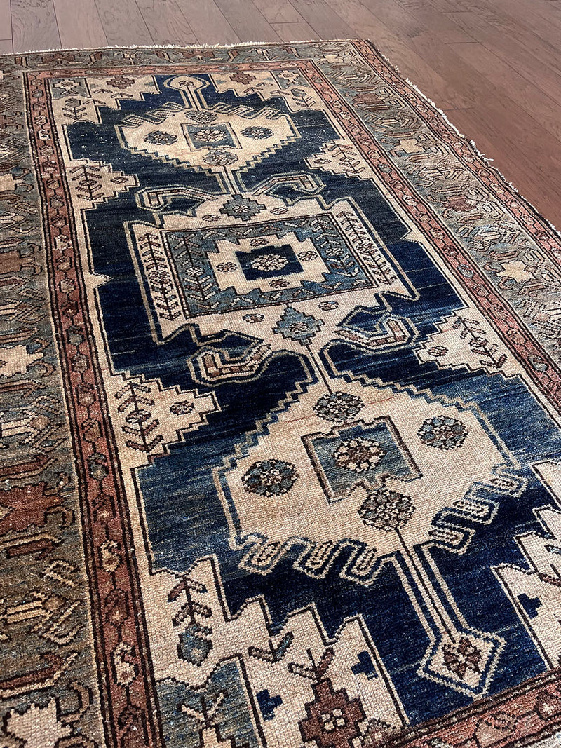 an antique malayer rug with a dark blue field, a large taupe medallion and a lilac border