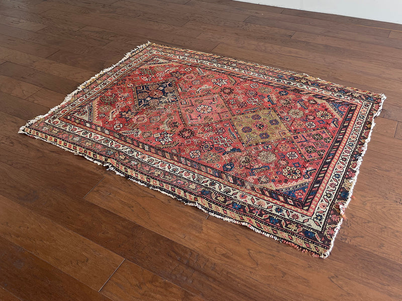 a vintage malayer rug with a raspberry pink field, lilac border and green and blue details