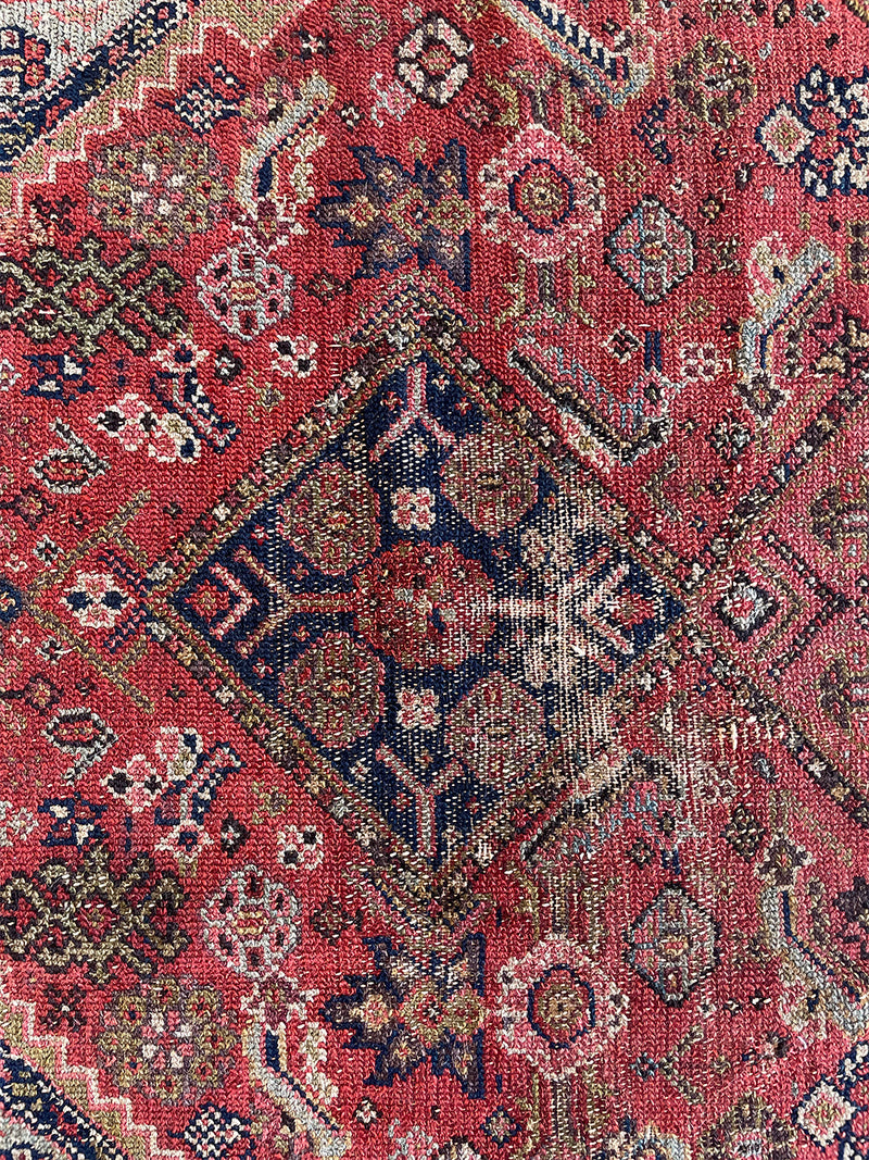 a vintage malayer rug with a raspberry pink field, lilac border and green and blue details