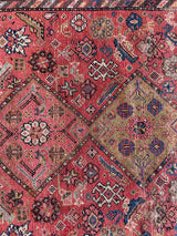 a vintage malayer rug with a raspberry pink field, lilac border and green and blue details